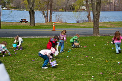 A group of children collecting Easter Eggs in front of a lake.