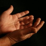 A close up of a person\'s hands on a black background.