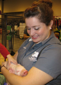A woman holding a small pig at River City Rodeo.