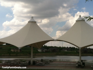 Two large umbrella features over benches at Lawrence Youngman Lake for the Omaha Photo Scavenger Hunt for kids.