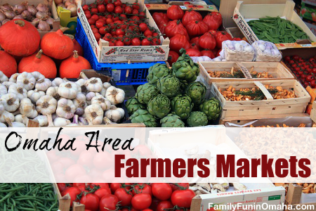 A variety of fresh fruit and vegetables on display at a farmers market with overlay text that reads Omaha Area Farmers Markets