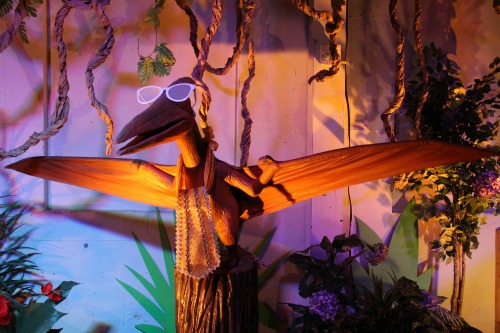 A Wooden sculpture of a dinosaur bird wearing sunglasses at Dinosaurs Rock at The Omaha Children\'s Museum.