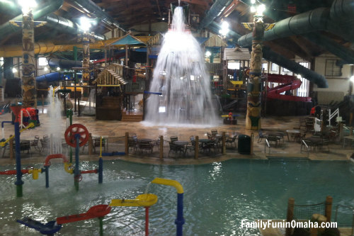 An indoor waterpark with splashing water from a bucket