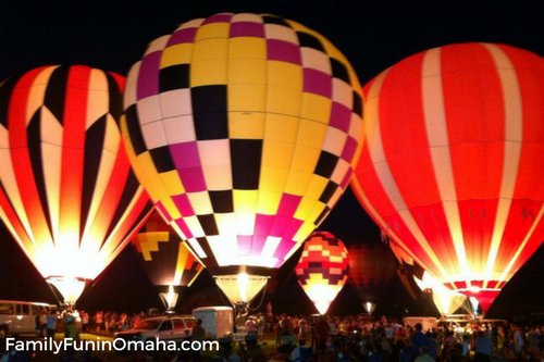 A group of hot air balloons lit up at night at the Midwest Hot Air Balloon Festivals.