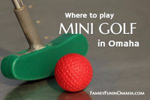 A close up of a green golf putter and a red golf ball with overlay text that reads \"Where to play mini golf in Omaha.\"