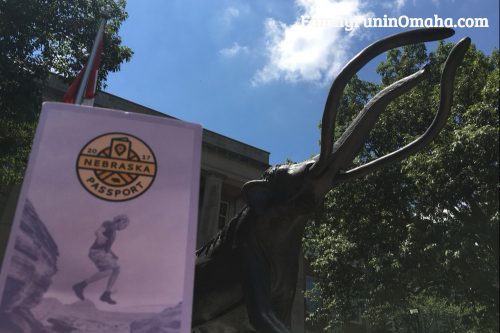 A sign in front of an animal statue that reads Nebraska Passport