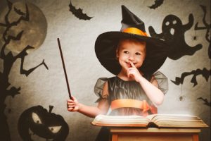 A little girl in a witch costume posing for a picture