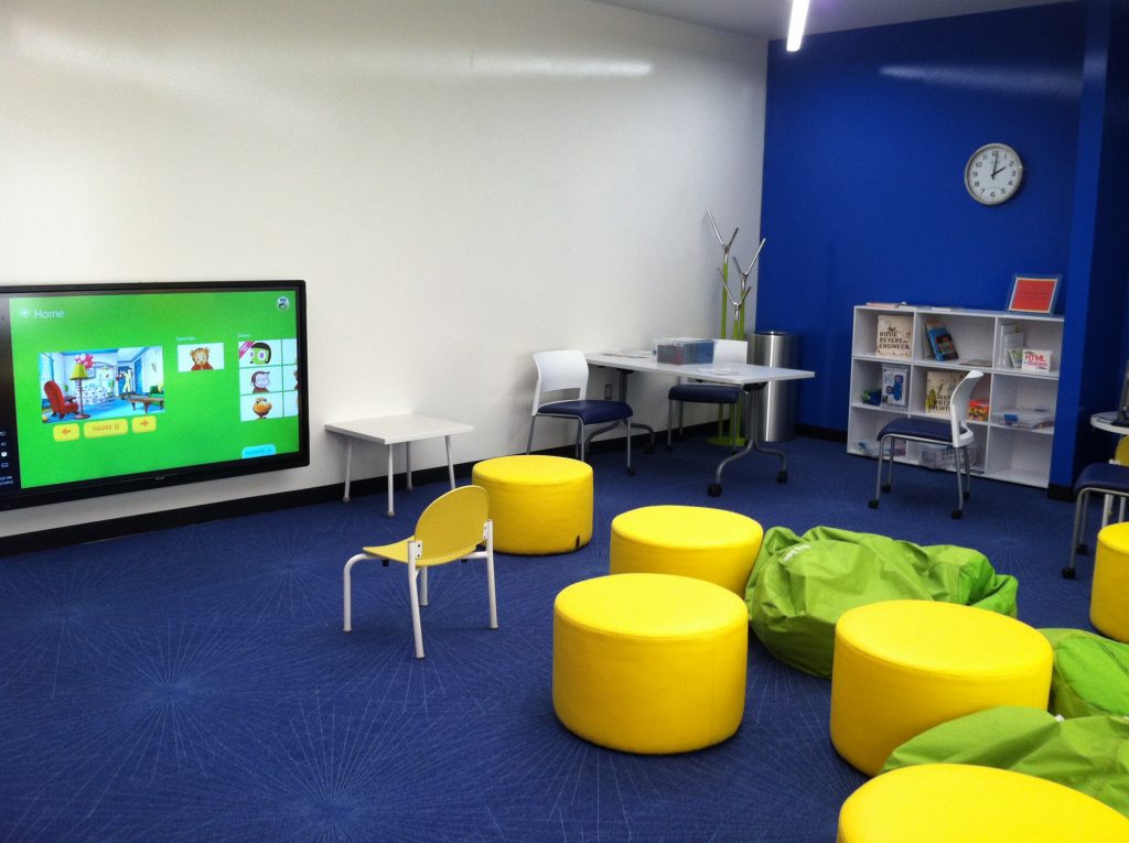 An indoor children\'s play area with books, tv, and comfortable seating