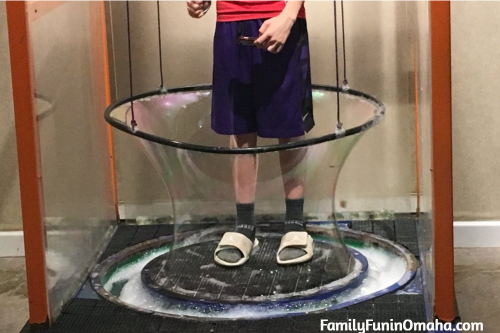 A person inside a bubble making exhibit at the St. Louis The Magic House.