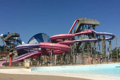 An outdoor waterpark slide by a shallow pool