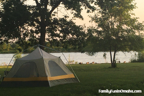 A gray tent on a grassy lot near a lake