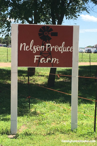 A sign on the side of a fence that reads Nelson Produce Farm.